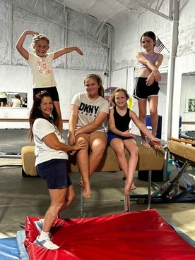 four gymnastics students and coach posed on a vault