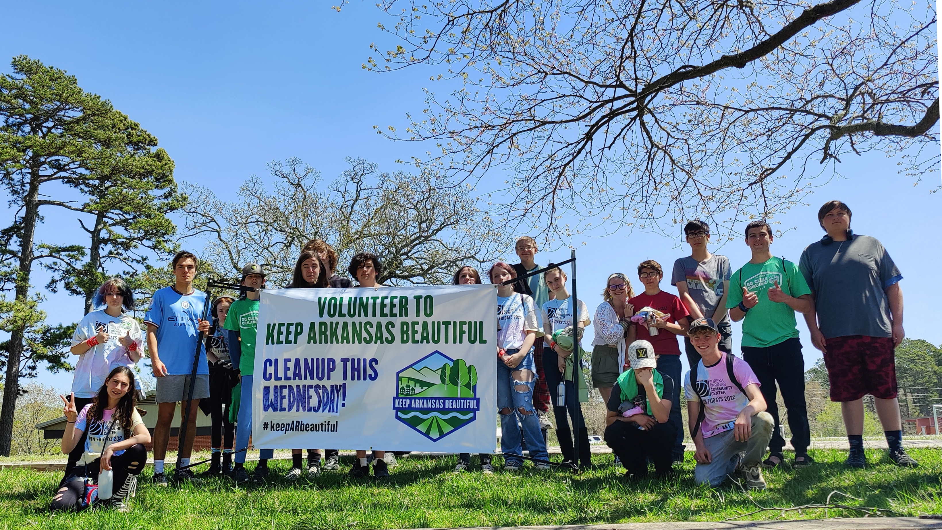 Group of people on grass with white and green sign