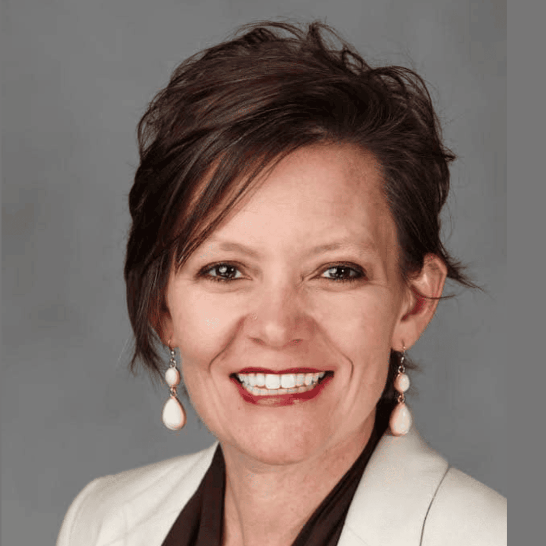 Woman smiling in white suit coat and earrings