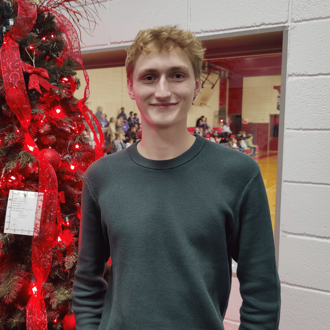 Man in green shirt beside tree with red decoration